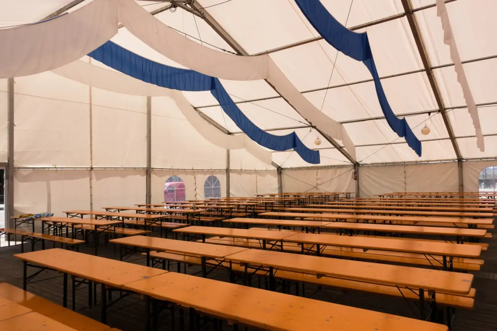 inside of a large white party tent with wooden benches