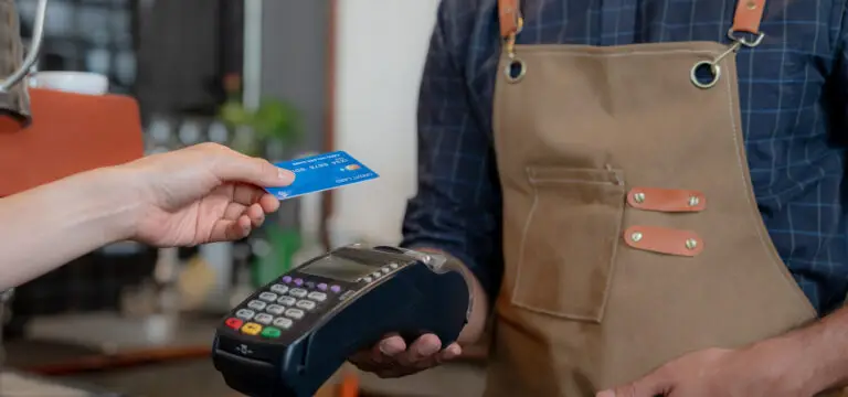 image of a man holding a credit card payment terminal and a woman tapping to pay